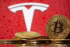 Representations of virtual currency Bitcoin are seen in front of Tesla logo in this illustration