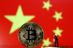 A small toy figurine is seen on representations of the Bitcoin virtual currency displayed in front of an image of China's flag in this illustration picture
