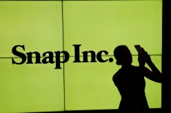 A woman stands in front of the logo of Snap Inc on the floor of the New York Stock Exchange (NYSE) in New York City, NY, U.S