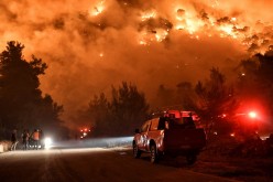 Flames rise as firefighters and volunteers try to extinguish a fire burning in the village of Schinos, near Corinth, Greece,