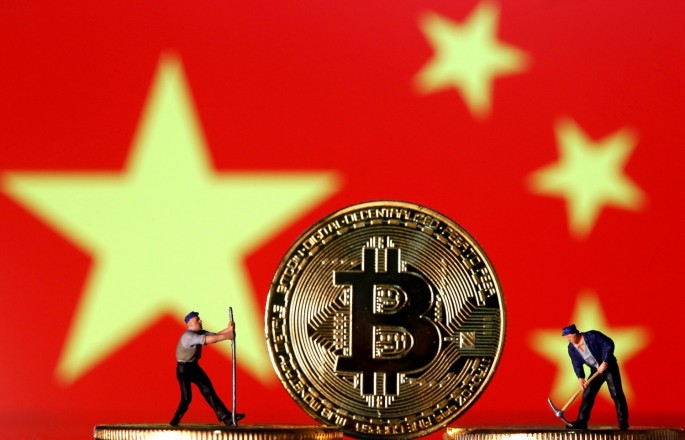 Small toy figurines are seen on representations of the Bitcoin virtual currency displayed in front of an image of China's flag in this illustration picture,