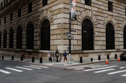 People walk wearing masks outside The Federal Reserve Bank of New York in New York City, U.S.,