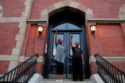 Protesters Bettye and Robert Freeman raise their fist from a doorstep as they watch a rally against the death in Minneapolis police custody of George Floyd in Boston