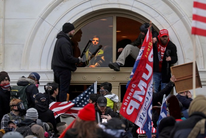 A mob of supporters of then-U.S. President Donald Trump climb through a window they broke as they storm the U.S. Capitol Building in Washington, U.S.,