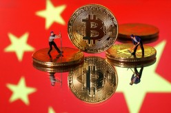 Small toy figurines are seen on representations of the Bitcoin virtual currency displayed in front of an image of China's flag in this illustration picture,