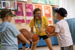 A counselor wearing a protective face mask plays with children as summer camps reopen amid the spread of coronavirus disease (COVID-19) at Carls Family