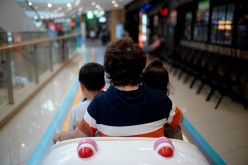A person sits in a toy car with children at a shopping mall in Shanghai, China
