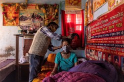 Suresh Kumar, 43, ties up the hair of his wife Pramila Devi, 36, who is suffering from the coronavirus disease (COVID-19), before taking her to a local government dispensary