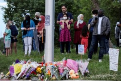 People gather at a makeshift memorial at the fatal crime scene where a man driving a pickup truck jumped the curb and ran over a Muslim family