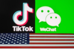 A U.S. flag is seen on a smartphone in front of displayed Tik Tok and WeChat logos in this illustration taken