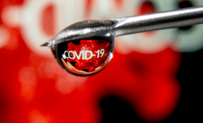 The word "COVID-19" is reflected in a drop on a syringe needle in this illustration taken