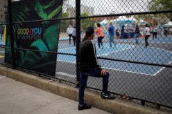 A man looks through a fence at a coronavirus disease (COVID-19) vaccination event for local adolescents and adults outside the Bronx Writing Academy school 