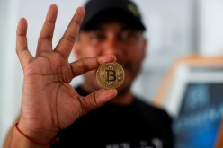 Bitcoin enthusiast Carlos Bonilla shows a physical representation of the cryptocurrency, at a Bitcoin Beach support office at El Zonte Beach in Chiltiupan,