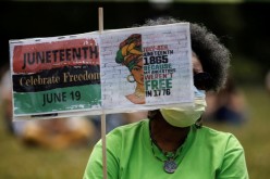 Norma Ewing of Seattle holds a sign as people gather at Judkins Park for Juneteenth, which commemorates the end of slavery in Texas,
