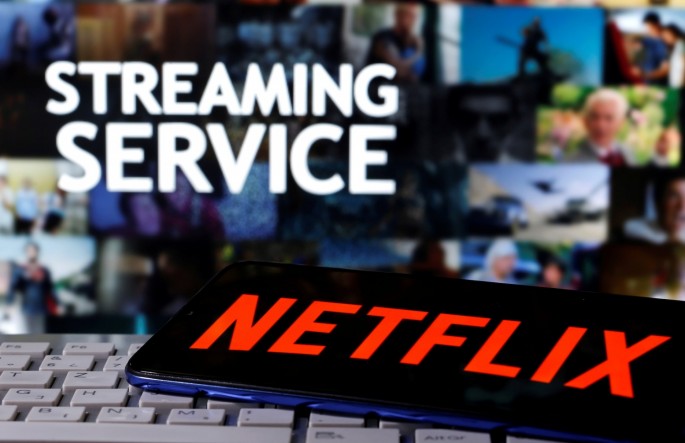 A smartphone with the Netflix logo is seen on a keyboard in front of displayed "Streaming service" words in this illustration taken