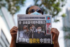 A supporter holds a copy of Apple Daily newspaper during a court hearing outside West Magistrates’ Courts