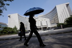 People walk past the headquarters of the People's Bank of China (PBOC), the central bank, in Beijing, China