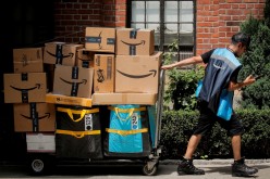 An Amazon delivery worker pulls a delivery cart full of packages during its annual Prime Day promotion in New York City, U.S