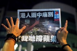 A supporter gestures while holding the final edition of Apple Daily in Hong Kong, China