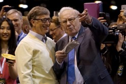 Berkshire Hathaway CEO Warren Buffett (R) shows his friend Microsoft co-founder Bill Gates the finer points of newspaper tossing, 
