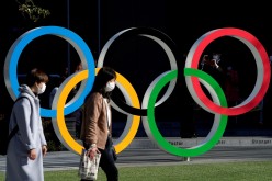 Women wearing protective face masks following an outbreak of the coronavirus disease (COVID-19) walk past the Olympic rings in front of the Japan Olympics Museum