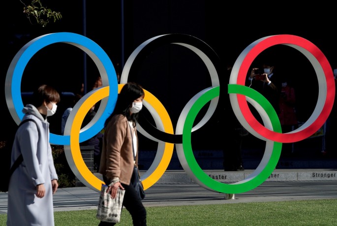 Women wearing protective face masks following an outbreak of the coronavirus disease (COVID-19) walk past the Olympic rings in front of the Japan Olympics Museum