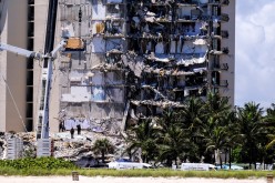 Search and rescue personnel with a rescue dog continue searching for victims days after a residential building partially collapsed in Surfside near Miami Beach,