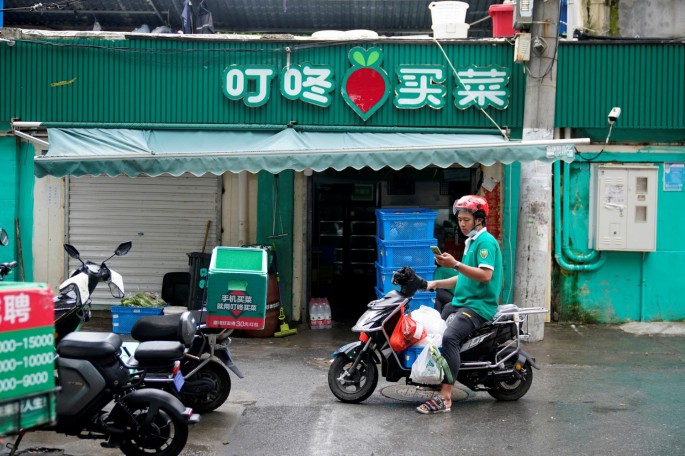 A delivery worker of Chinese online grocery Dingdong Maicai works at a shop on a street in Shanghai, China 