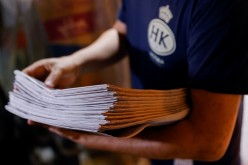 A supporter purchases copies of the Apple Daily newspaper from a newspaper stall after it looked set to close for good by Saturday following police raids 