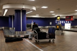 A baggage claim employee grabs bags from an empty baggage claim area in Delta terminal at LaGuardia Airport in New York, U.S