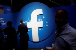 Attendees walk past a Facebook logo during Facebook Inc's F8 developers conference in San Jose, California, U.S