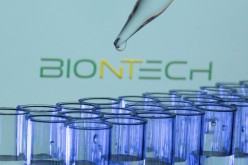 Test tubes are seen in front of a displayed Biontech logo in this illustration taken