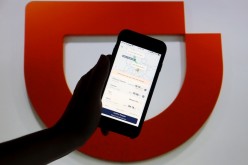 The app of Chinese ride-hailing giant Didi is seen on a mobile phone in front of the company logo displayed in this illustration picture
