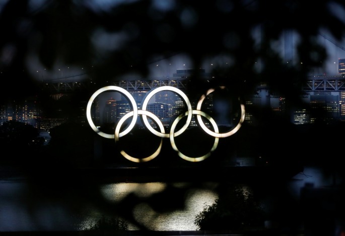 The giant Olympic rings are seen through a tree in the dusk at the waterfront area of Odaiba Marine Park, before the opening ceremony of the 2020 Tokyo Olympic Games