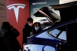 Visitors wearing face masks check a China-made Tesla Model Y sport utility vehicle (SUV) at the electric vehicle maker's showroom in Beijing, China