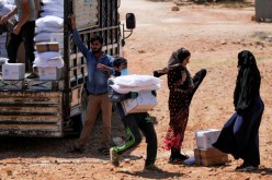 A worker holds bags and a box of humanitarian aid in the opposition-held Idlib,