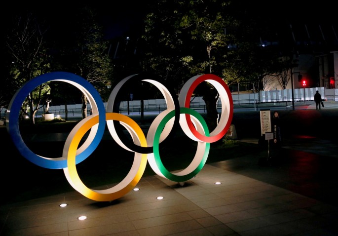 The Olympic rings are illuminated in front of the National Stadium in Tokyo, Japan