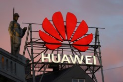 The logo of the Chinese telecommunications giant Huawei Technologies is pictured next to a statue on top of a building in Copenhagen, Denmark,