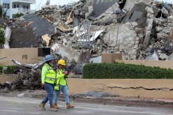 Rescue workers walk past debris after the managed demolition of the remaining part of Champlain Towers South complex as search-and-rescue efforts continue in Surfside,