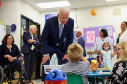 U.S. President Joe Biden flanked by President of McHenry County College Clint Gabbard and Senator Tammy Duckworth, speaks with a child,