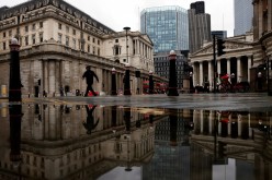 The Bank of England and Royal Exchange are reflected in a puddle as a pedestrian walks past, amid the coronavirus disease (COVID-19) outbreak in London, Britain