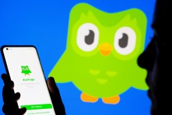 Woman with her smartphone poses in front of displayed Duolingo logo in this illustration taken, 