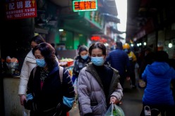 People wearing face masks walk on a street market, following an outbreak of the coronavirus disease (COVID-19) in Wuhan, Hubei province, China 