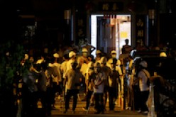 Men in white T-shirts and carrying poles are seen in Yuen Long after attacking anti-extradition bill demonstrators at a train station in Hong Kong, 