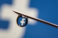 Facebook logo is reflected in a drop on a syringe needle in this illustration photo taken