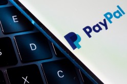 A smartphone with the PayPal logo is placed on a laptop in this illustration taken on