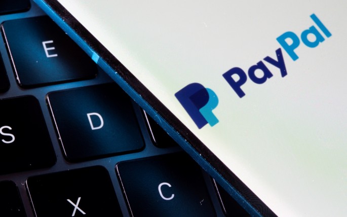 A smartphone with the PayPal logo is placed on a laptop in this illustration taken on