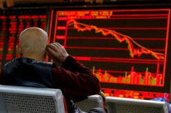 An investor sits in front of a board showing stock information at a brokerage office in Beijing, China,