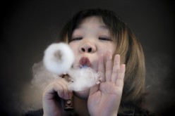 A saleswoman demonstrates vaping at the Vape Shop that sells e-cigarette products in Beijing, China