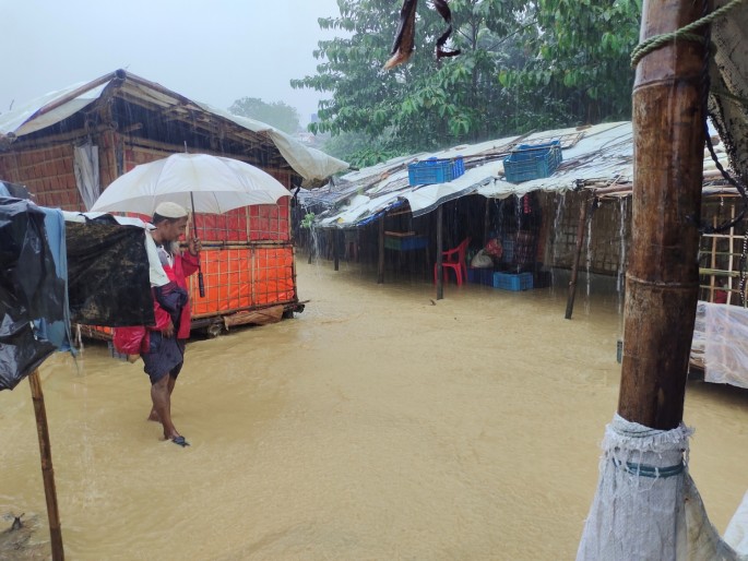 A man walks in a flooded street after heavy monsoon rains triggered flooding at Kutapalong refugee camp,